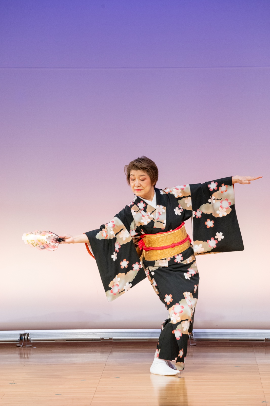 扇を広げ、黒地に桜柄の着物で舞う現代日本舞踊の演者