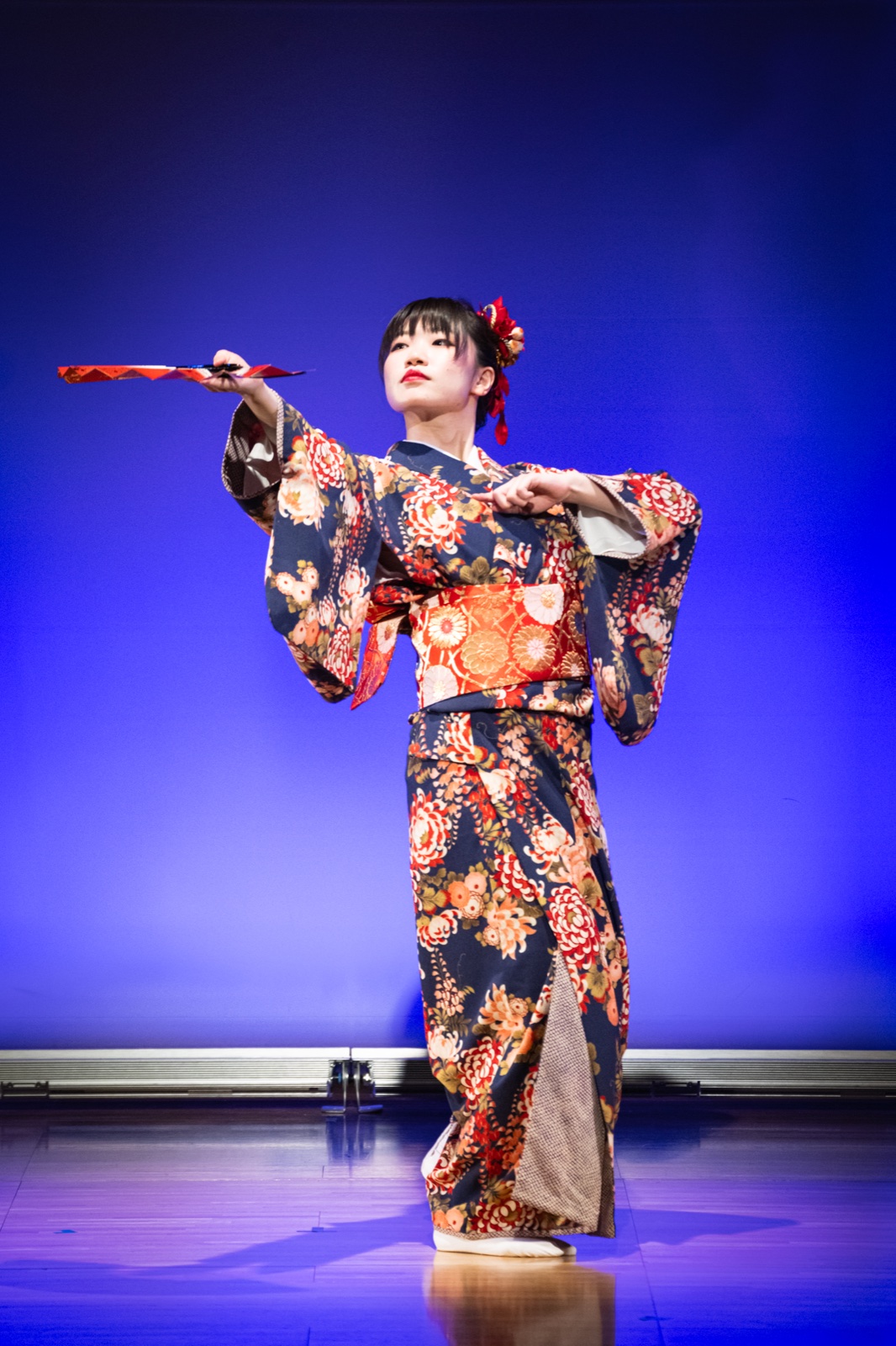 青い舞台で扇を手に舞う現代日本舞踊の演者